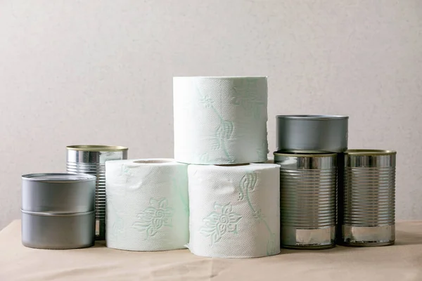 Supplies crisis emergency food stock for quarantine isolation period. Cans of canned food and toilet paper on table.