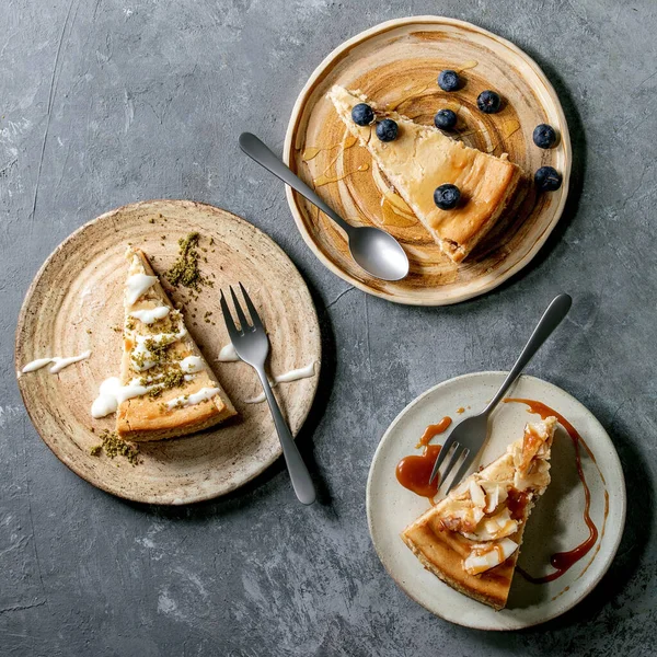 Pezzi Cheesecake Con Guarnizioni Decorazioni Diverse Piatti Ceramica Con Forchette — Foto Stock