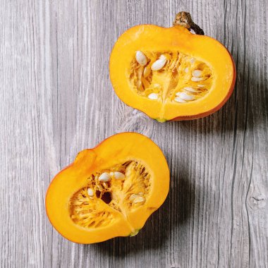 İki parça çiğ organik hokkaido kabağı ve gri ahşap arka planda tohumlar. Düz uzanış, boşluk