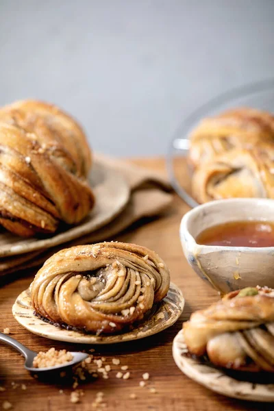 传统的瑞典红豆蔻甜面包放在盘子里 陶瓷碗里的配料放在木桌上 — 图库照片