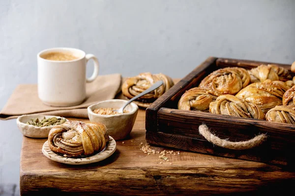 伝統的なスウェーデンのカルダモン甘いパン木製のトレイでKanelbulle コーヒーカップ 木製のテーブルの上にセラミックボウルの成分 — ストック写真