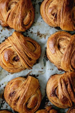 Taze pişmiş geleneksel İsveç tarçınlı tatlı çörekler fırın tepsisinin üzerinde kağıt pişirerek Kanelbulle.