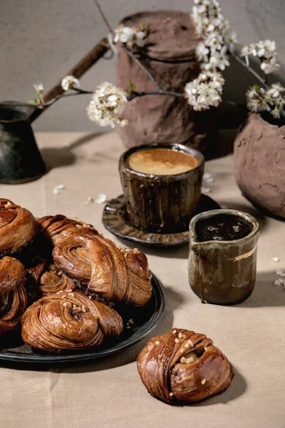 伝統的なスウェーデンのシナモン甘いパンヴィンテージトレイのKanelbulle コーヒーカップ シロップのジャグ リネンテーブルクロスの花の枝 — ストック写真