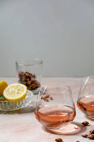 ピンクのバラのシャンパン サイダーまたはレモネードのカクテルグラスにドライローズの芽とレモン ピンク大理石の背景 — ストック写真