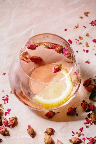 粉红色玫瑰香槟 苹果酒或柠檬水配干玫瑰芽和柠檬的鸡尾酒杯 粉色大理石背景 靠近点 — 图库照片