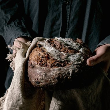 Siyah gömlekli adam el ele tutuşmuş taze fırınlanmış zanaatkar. Ev yapımı çikolata ve keten kumaş üzerinde yabanmersini ekmeği..