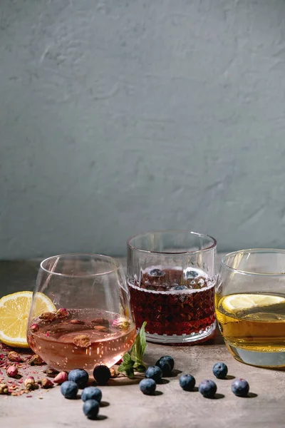 不同的鸡尾酒杯 配上色彩艳丽的饮料 粉色玫瑰香槟 苹果酒或柠檬水 干玫瑰芽 蓝莓和薄荷 上面的成份 灰色纹理背景 — 图库照片