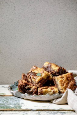 Brookies çikolatalı kekler ve ev yapımı kekler eski beyaz ahşap masada seramik tabakta kareler tarafından dilimlenmiş. Boşluğu kopyala