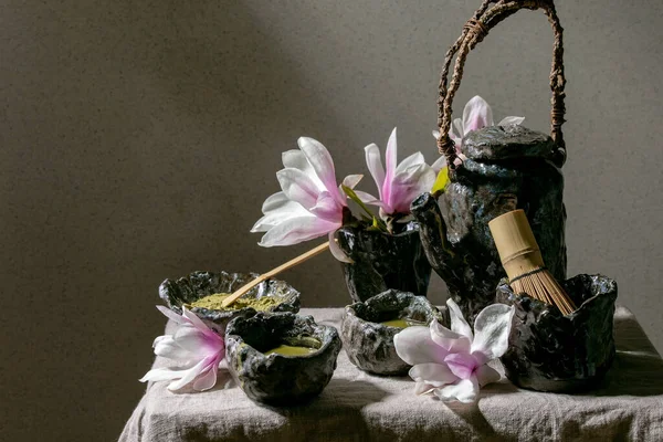 Faça uma chaleira de cerâmica artesanal e uma xícara wabi-sabi de chá verde  quente sobre musgo com galhos secos e folhas. cerimônia do chá de natureza  outonal.