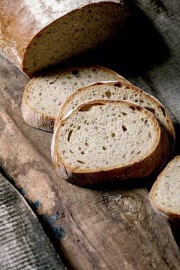 Eski ahşap zemin üzerinde dilimlenmiş tahıllı çavdar-buğday organik ekmeği. Kapat.