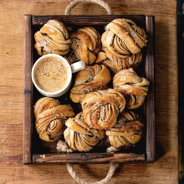 伝統的なスウェーデンのカルダモンやシナモンの甘いパン木製のトレイにKanelbulle 木製のテーブルの上にコーヒーカップ — ストック写真