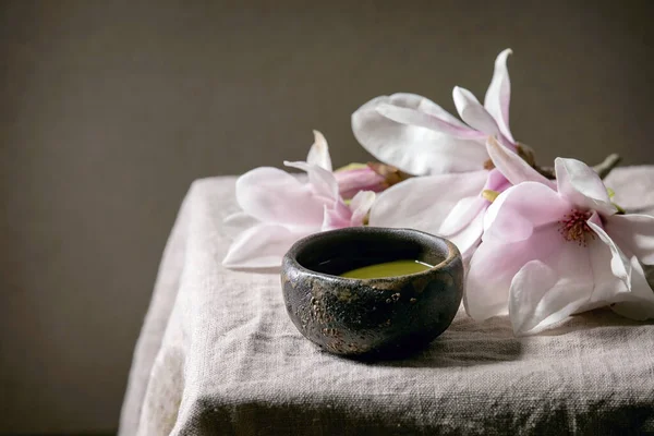 日本马茶茶绿茶 乌头沙比陶瓷杯 粉红色木兰花 灰色亚麻布桌布 — 图库照片
