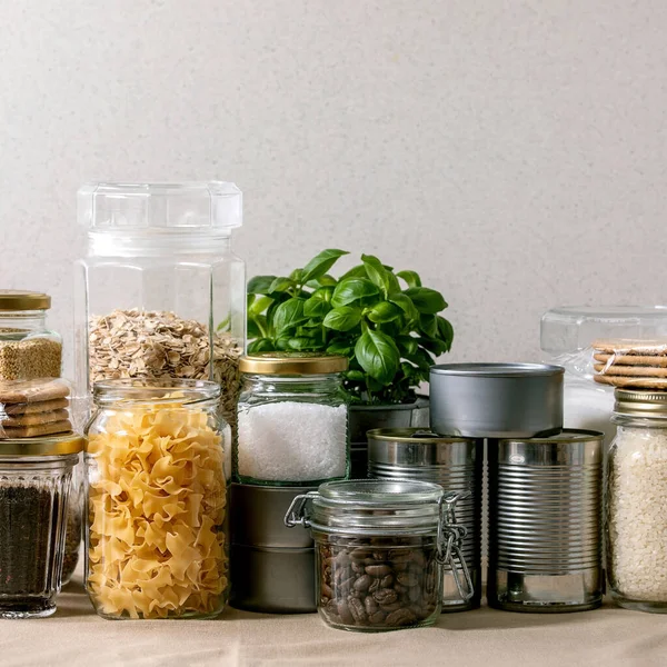 Food supplies crisis food stock for quarantine isolation period. Different glass jars with grains, pasta, cans of canned food, toilet paper, chalkboard handwritten chalk lettering Stay home and relax.