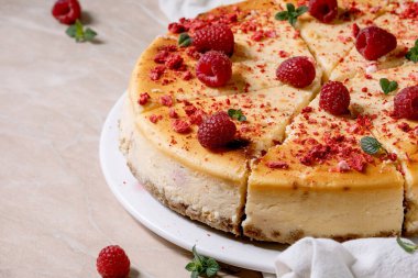 Ev yapımı ahududu fırınlanmış cheesecake taze ahududu ile süslenmiş tabakta ve pembe mermer arka planda beyaz bezle süslenmiş nane şekeri. Kapat.