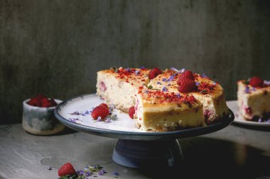 Ev yapımı ahududu fırınlanmış cheesecake taze ahududu ve gri masada nane şekeri ile süslenmiş tabakta. Düz uzanış, boşluk
