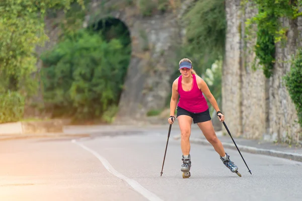 Hermosa chica rubia deportiva con Rollerblade y palo de escalada — Foto de Stock