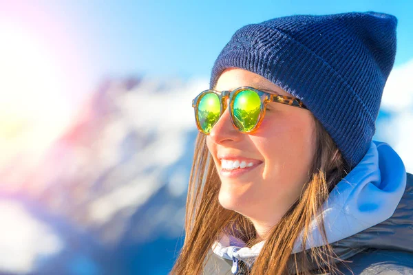 Kobieta narciarz z nartami, uśmiechając się i noszenie okularów narciarskich — Zdjęcie stockowe