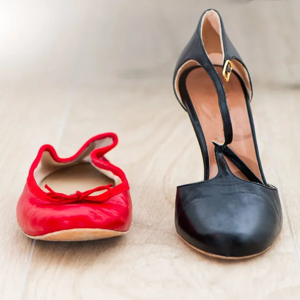 Chaussures rouges ballerines et talons noirs à proximité — Photo