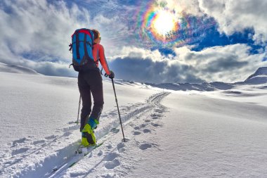 Girl makes ski mountaineering alone toward the mountain pass clipart
