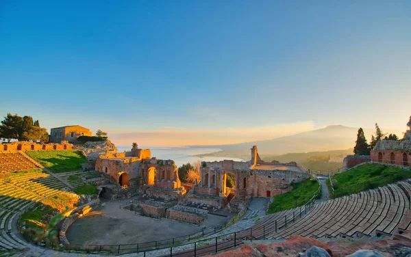 Teatro antigo de Taormina com Etna vulcão em erupção ao pôr do sol — Fotografia de Stock