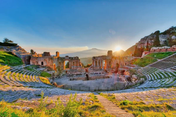 Antiguo teatro de Taormina con Etna volcán en erupción al atardecer — Foto de Stock