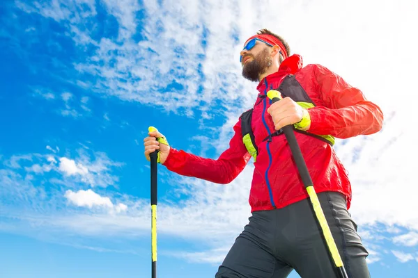 Homem com paus entre a caminhada nórdica com fundo céu — Fotografia de Stock