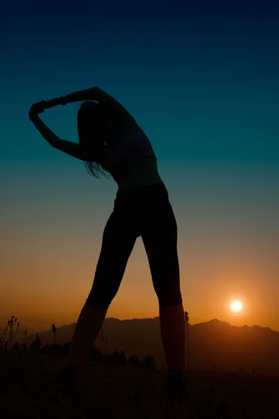 Praticare ginnasta ragazza al tramonto verso il sole — Foto Stock