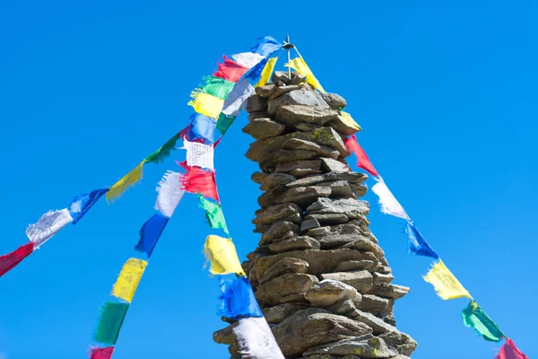 Colorful Tibetan Buddhist prayer flags hanging on a stone pile o — Stock Photo, Image