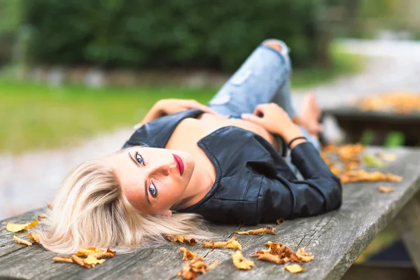 Sexy blondes nacktes Mädchen liegt im Herbst auf einer Holzbank — Stockfoto