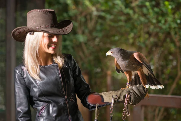 Vacker blond kvinna håller en harris hawk på en skyddande glo — Stockfoto