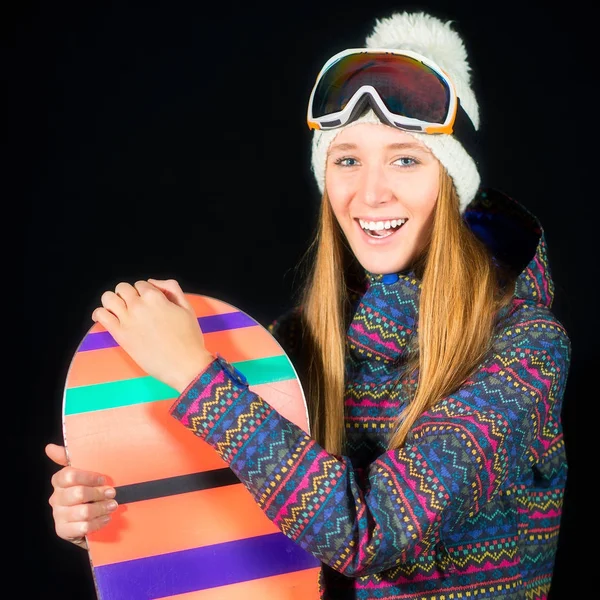 Улыбающаяся девушка в лыжной одежде со сноубордом на черном бэкгре — стоковое фото