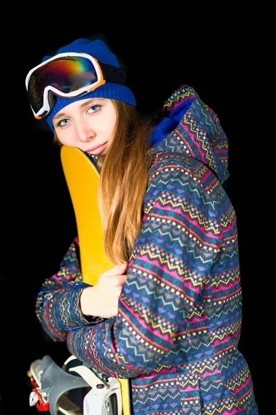 Νεαρό κορίτσι αγκαλιάζει snowboard της στο studio σε μαύρο φόντο — Φωτογραφία Αρχείου