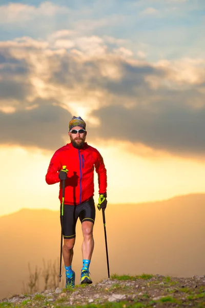 Sportler üben Trail mit Stöcken bei Sonnenuntergang senkrecht imag — Stockfoto
