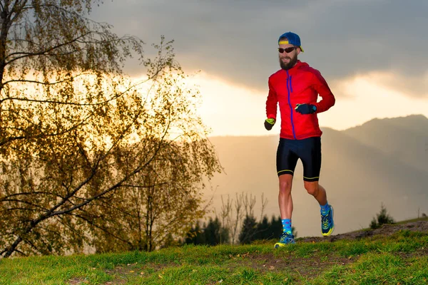 Atleet wordt uitgevoerd in de bergen bij zonsondergang — Stockfoto