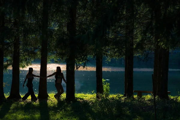 Pretty free hippie girls walking through the woods. Lake view - — Stock Photo, Image