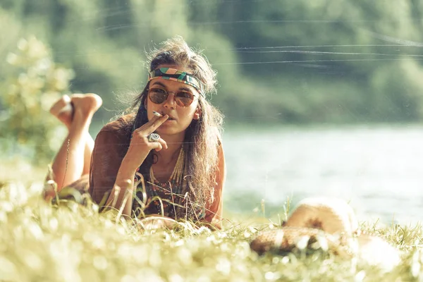Прелестная девушка-хиппи, курящая на траве - эффект винтажа — стоковое фото