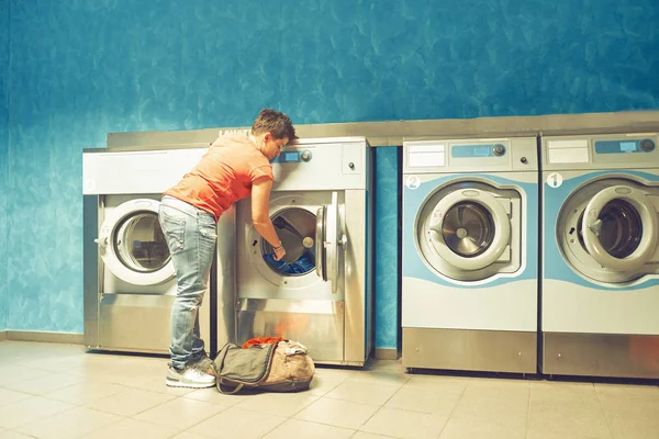 A girl fills up a public automatic washing machines with dirty c Stock Picture