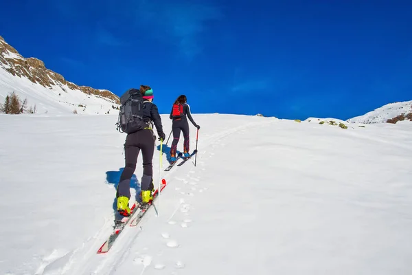 Esquí montañismo dos chicas cuesta arriba hacia una montaña — Foto de Stock