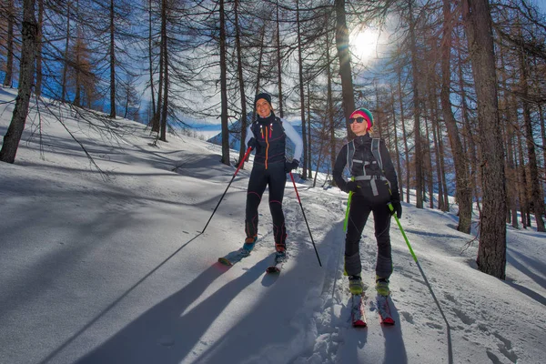 Dos chicas en el bosque con esquís de montaña ascienden — Foto de Stock