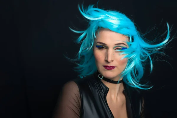 Una chica sobre un fondo negro con peluca azul y pelo en el viento — Foto de Stock