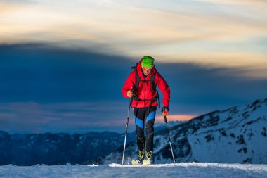Ski touring at night in the last hours of the day clipart