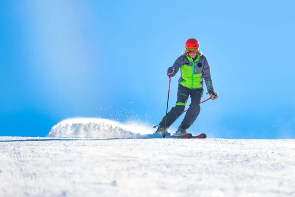 En bra skidåkare i aktion flyttar den dammiga snön till banan — Stockfoto