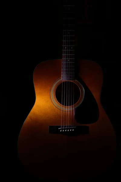 在光线或阴影之间的黑色背景上的声学吉他细节 — 图库照片
