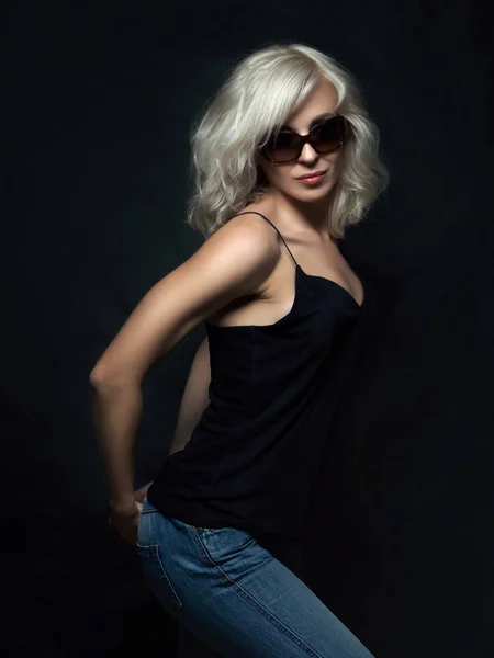 Piękna Blondynka kobieta nosi okulary, pozowanie na czarny grzbiet — Zdjęcie stockowe