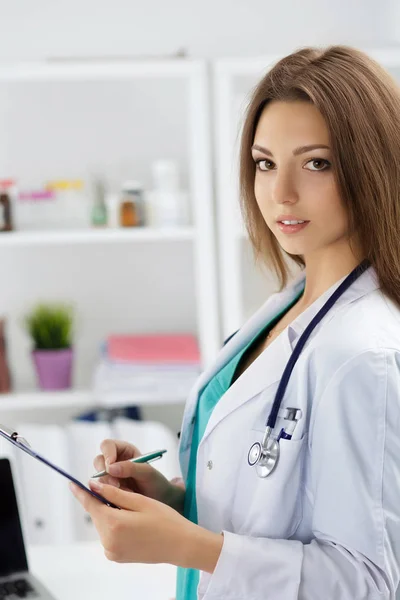 Médico femenino rellenando la historia clínica del paciente —  Fotos de Stock