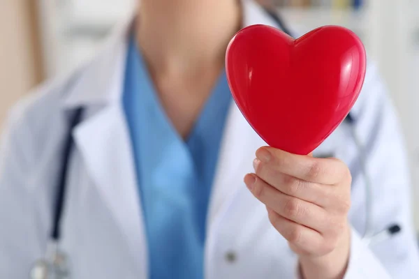 Лікарка-жінка тримає в руках червоне іграшкове серце крупним планом — стокове фото