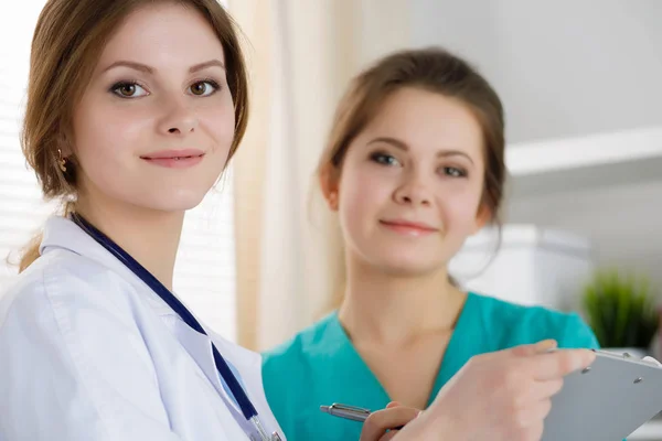 Two beautiful female medicine doctors working at their office