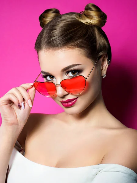 Young woman looks over heart shaped glasses — Stock Photo, Image