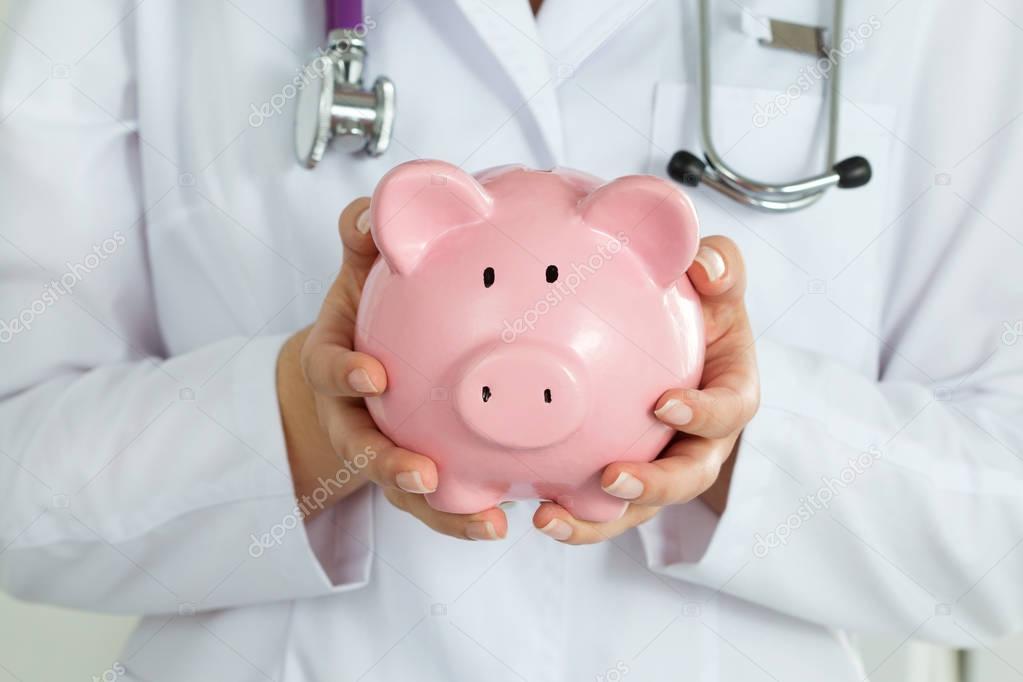 Female doctor holding piggy bank