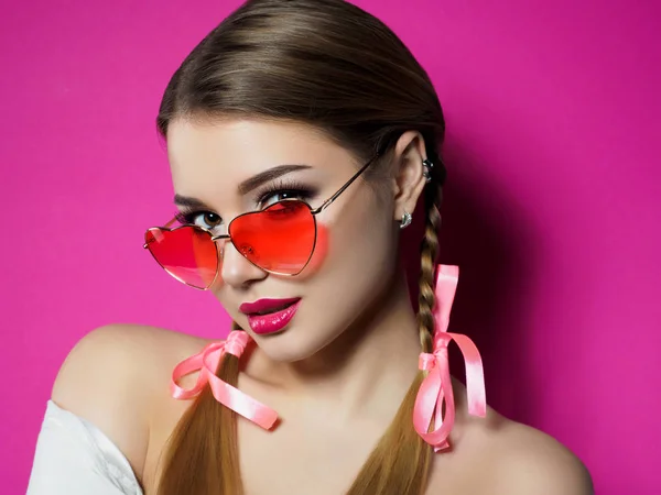 Young woman looks over heart shaped glasses — Stock Photo, Image